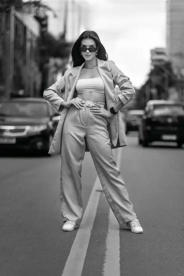 Black and white photo of a stylish woman posing confidently in urban streets of Belo Horizonte, Brazil.
